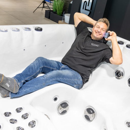 Mann entspannt im leeren Whirlpool mit Handy.